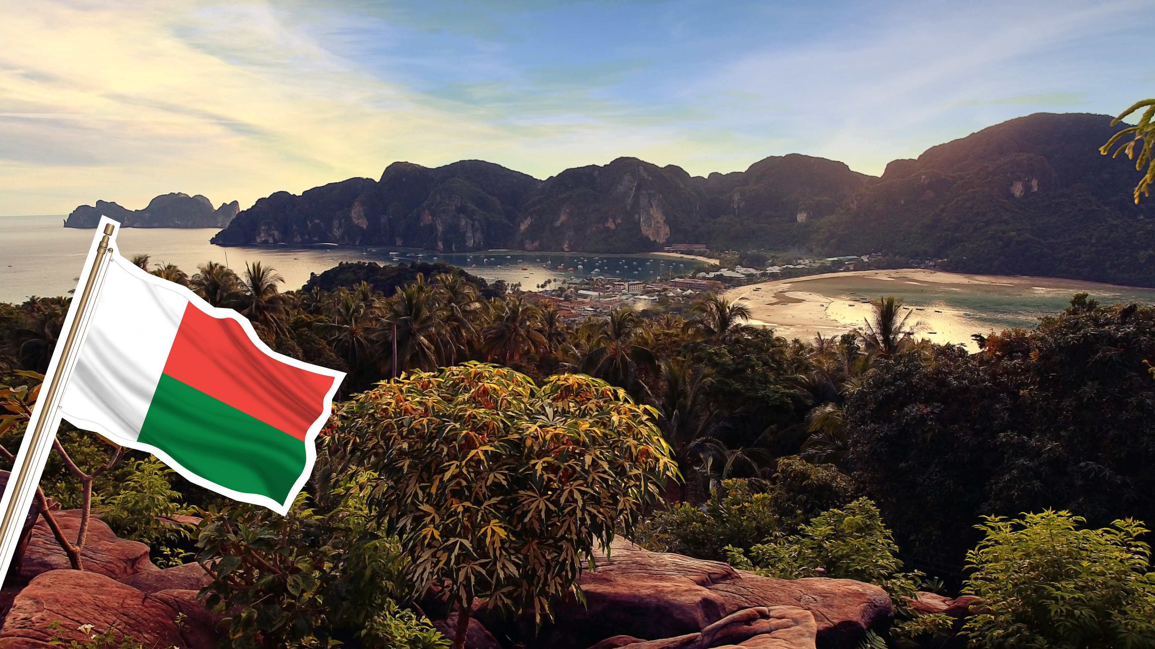 Eine Landschaft in Madagaskar mit viel Grün und Strand und einer Flagge.