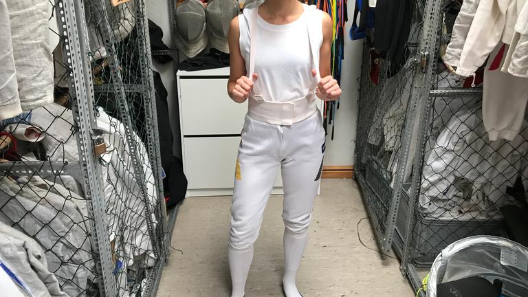 Maral zieht sich eine Hose zum Fechten an.
