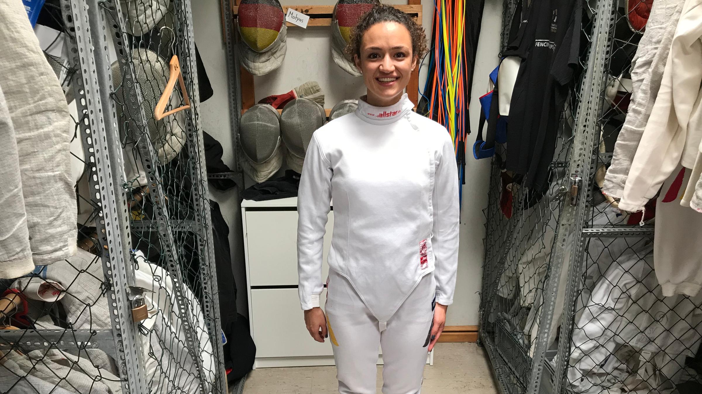 Maral zieht eine Jacke zum Fechten an.