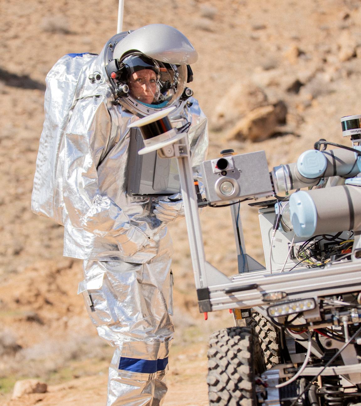 Eine Astronautin steht in einer Felsigen Landschaft in Armenien und probt eine Marsmission.