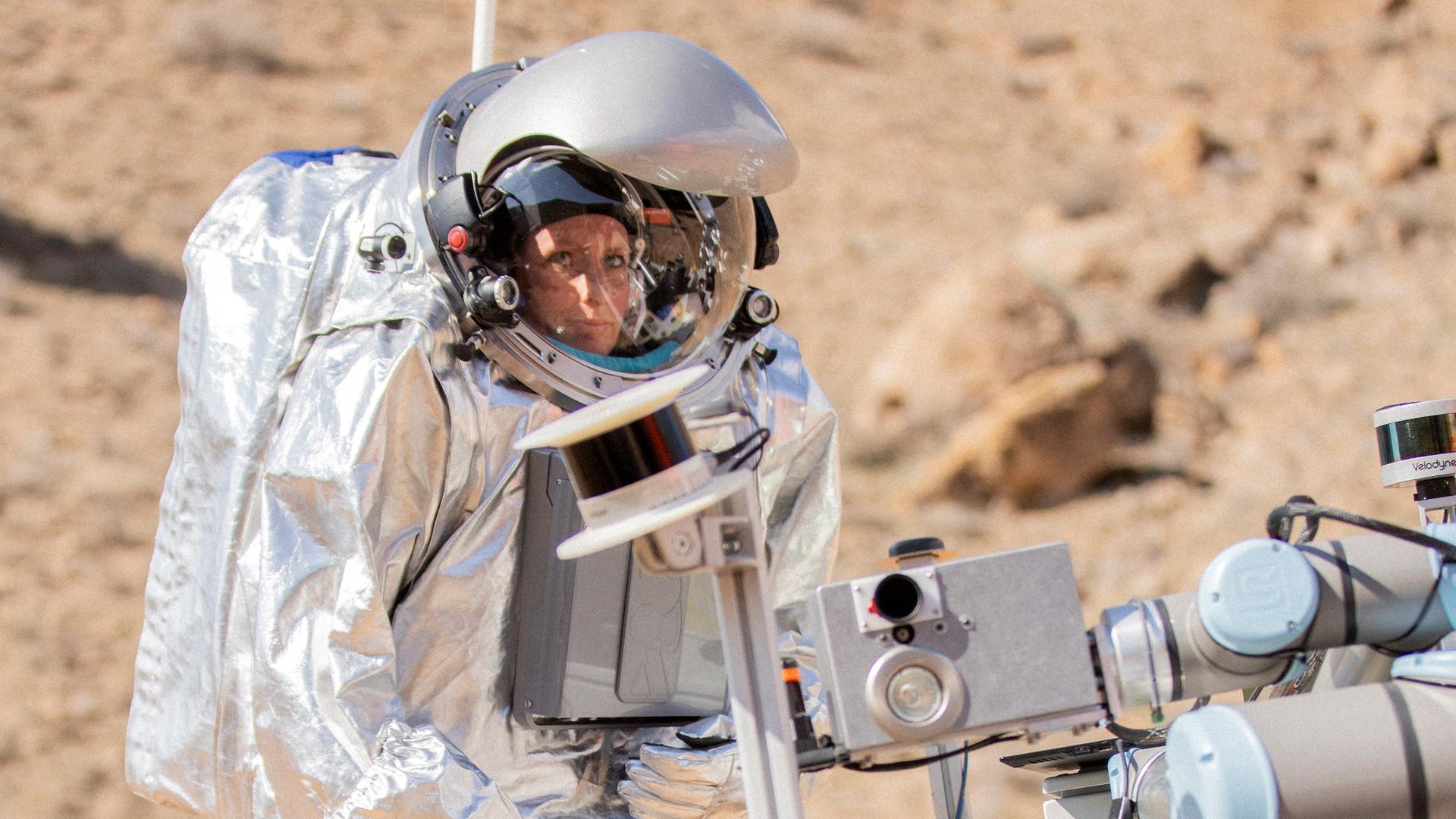 Eine Astronautin steht in einer Felsigen Landschaft in Armenien und probt eine Marsmission.