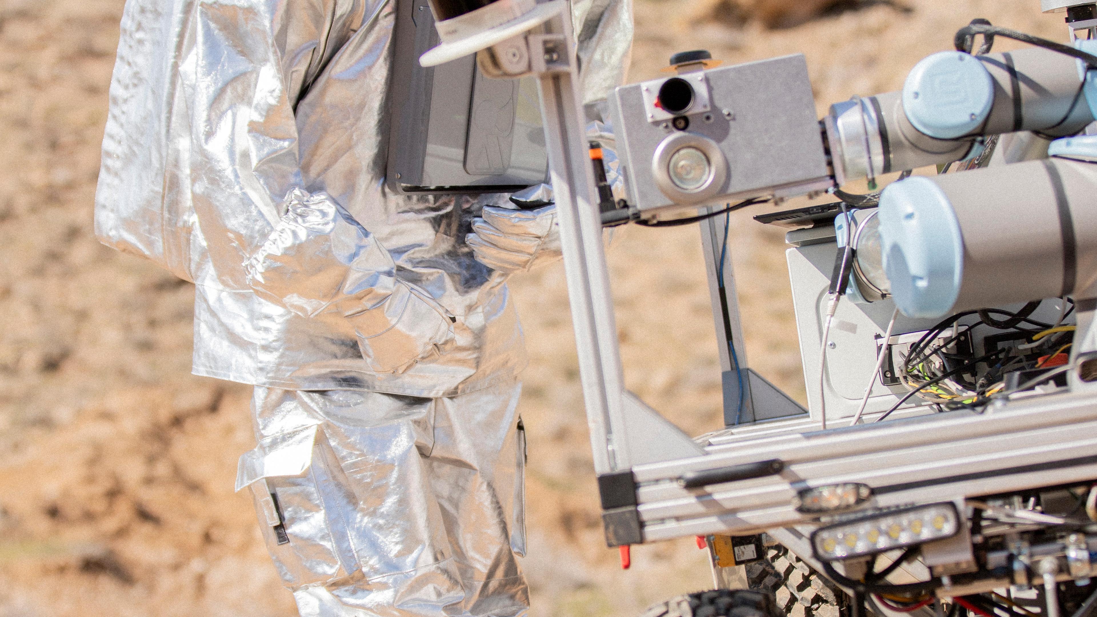 Eine Astronautin steht in einer Felsigen Landschaft in Armenien und probt eine Marsmission.