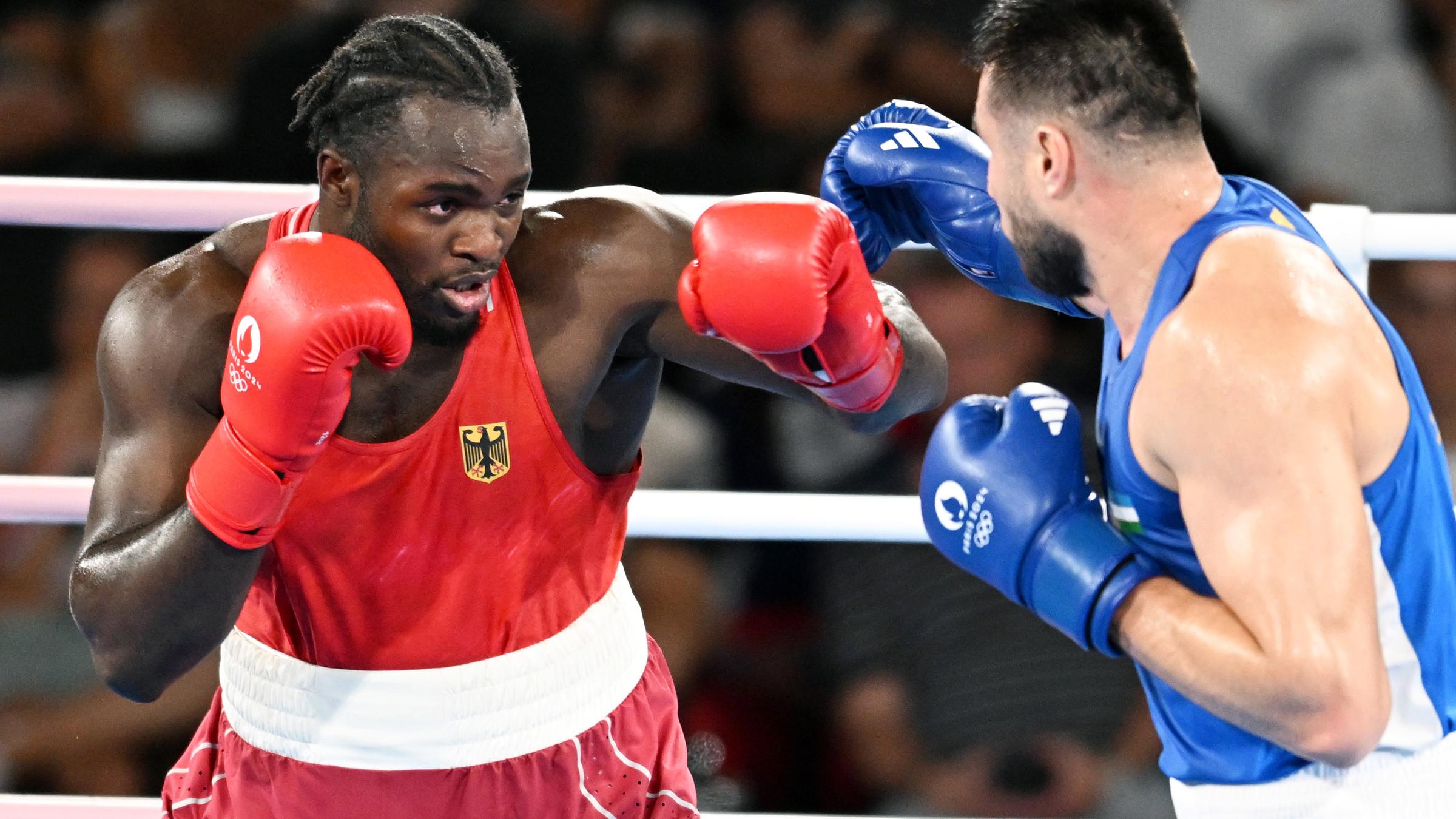 Rot gekleideter Boxer boxt gegen blau gekleideten Boxer