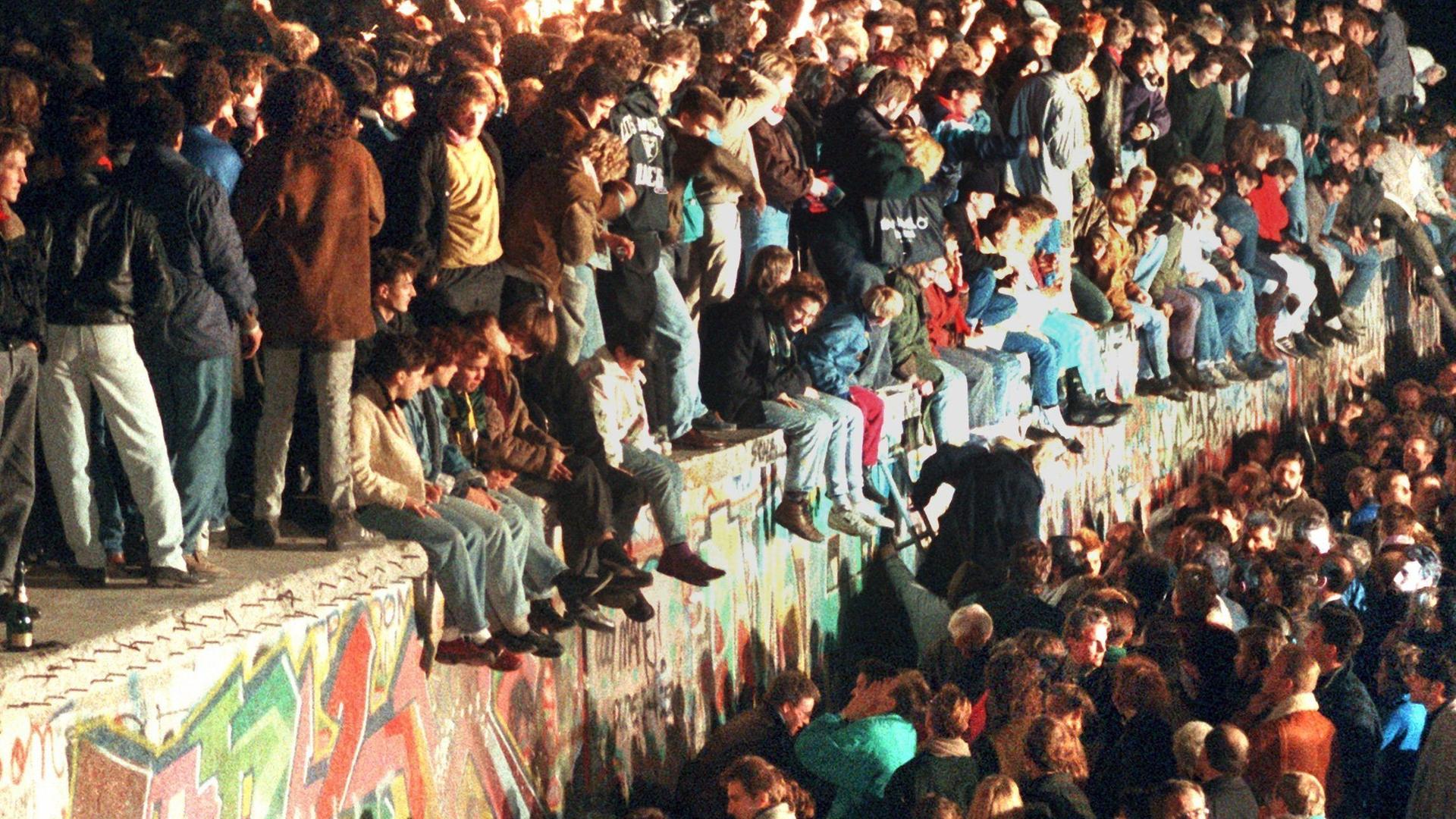 Jubende Menschen auf der Berliner Mauer