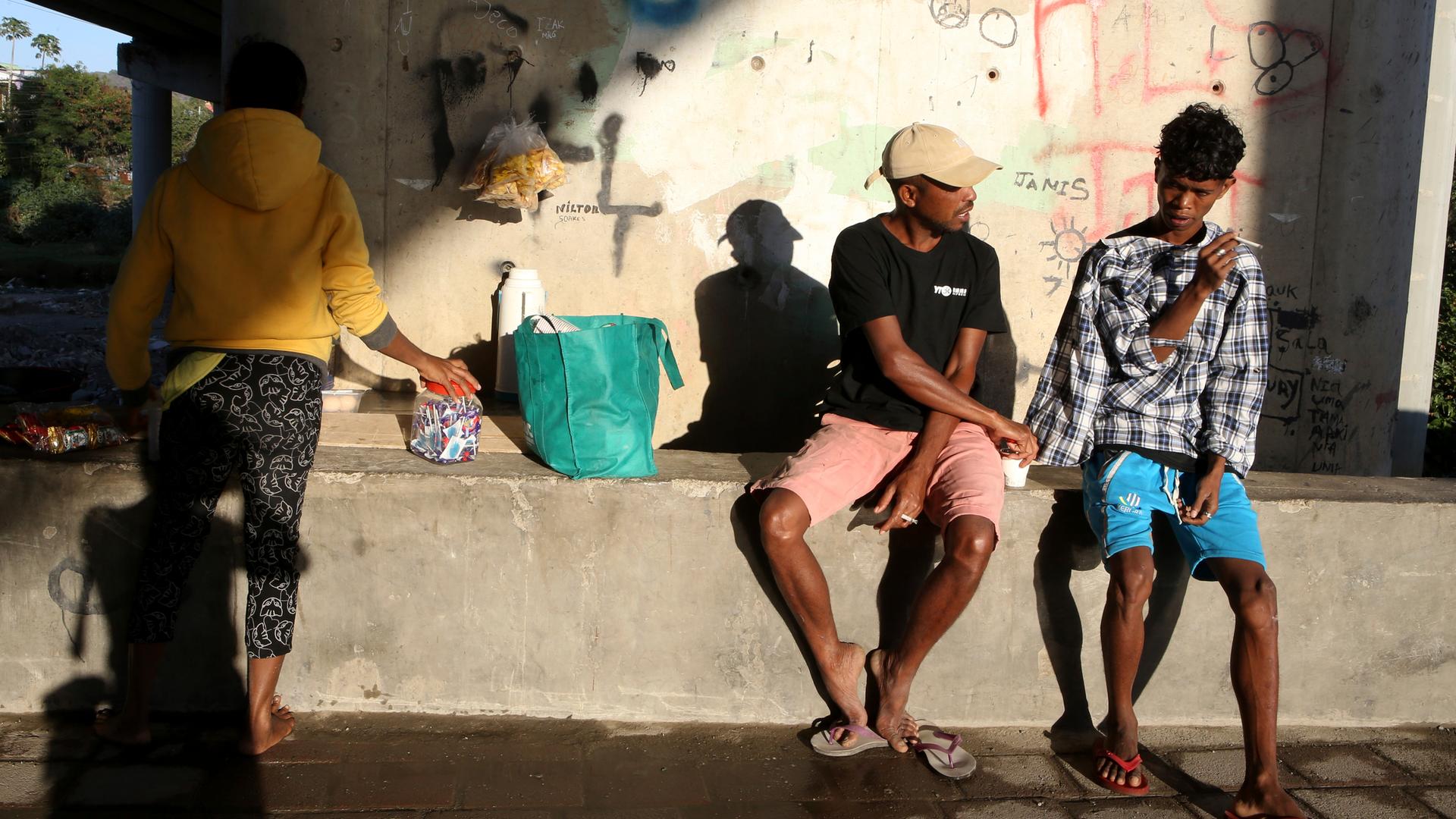 Menschen sitzen unter einer Brücke 