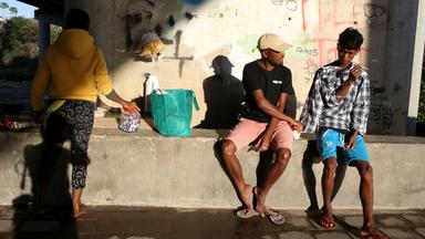 Menschen sitzen unter einer Brücke 