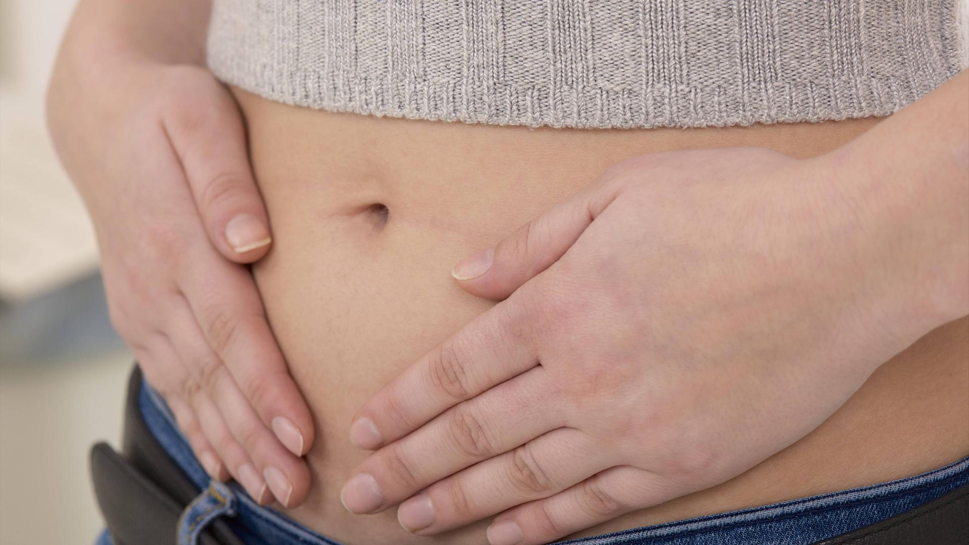 Frau hält sich Hände auf den Bauch