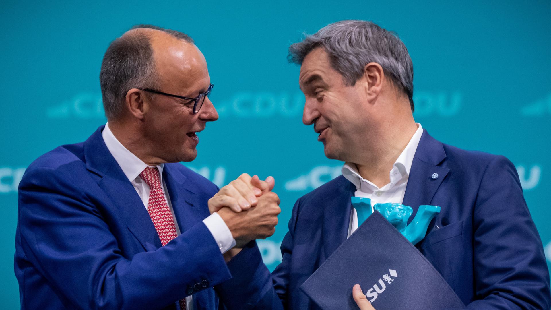 Berlin: Friedrich Merz (l), CDU-Bundesvorsitzender, gibt Markus Söder (CSU), Ministerpräsident von Bayern, nach dessen Rede beim CDU-Bundesparteitag im Mai die Hand.