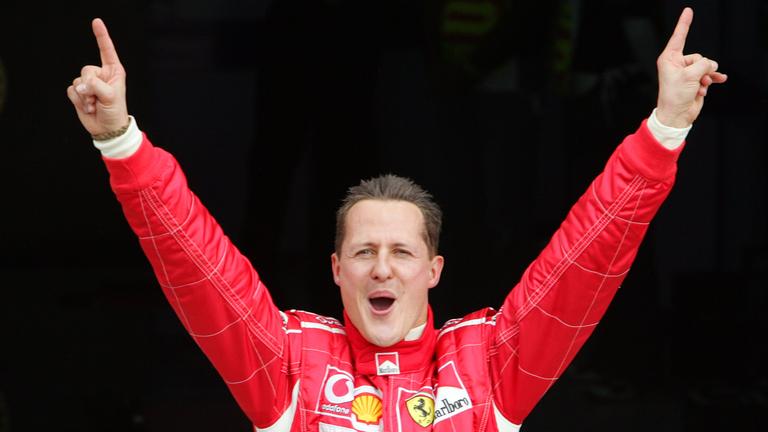Auf dem Bild sieht man Michael Schumacher, wie er die Arme hochreißt und jubelt. 