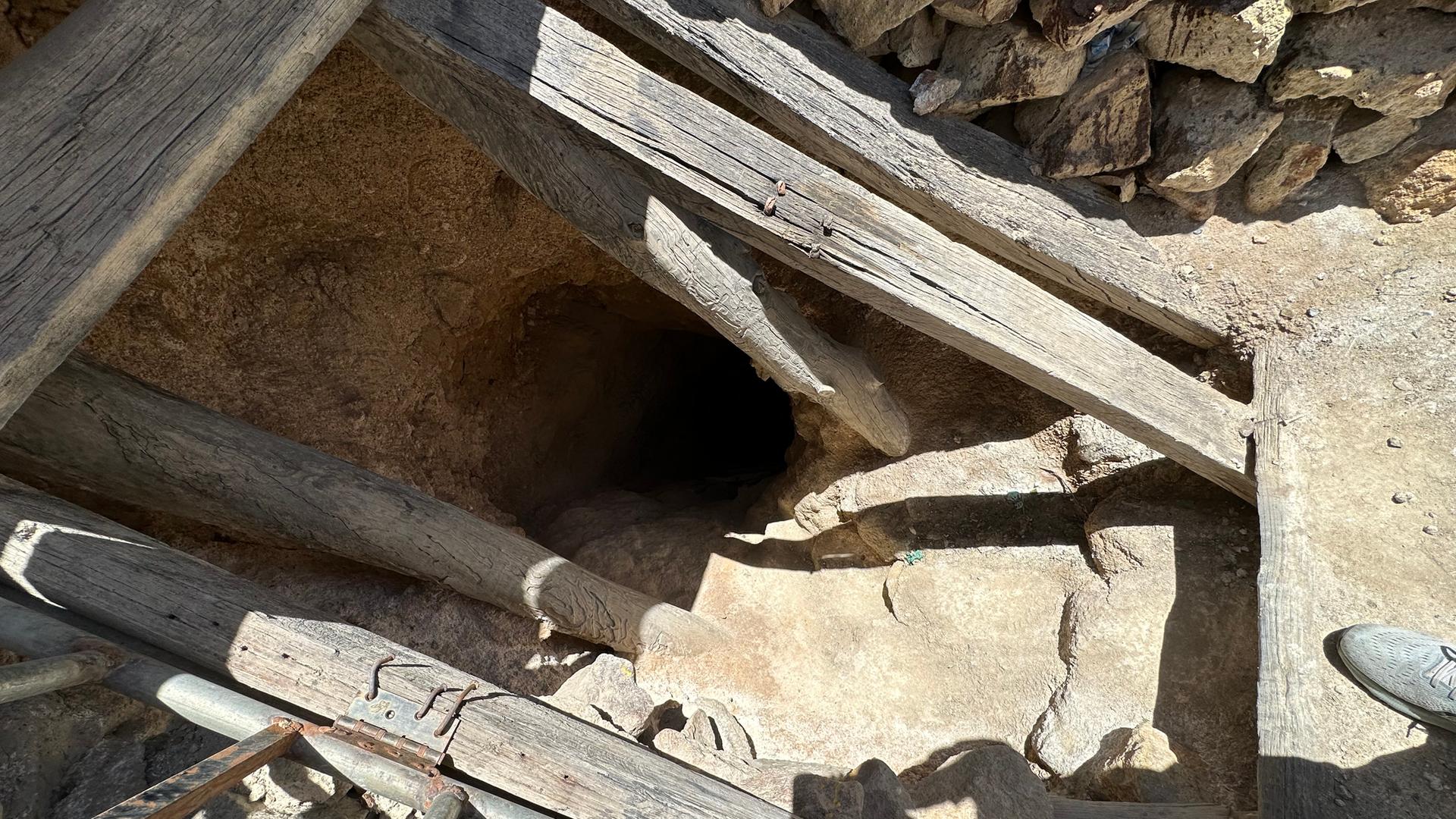 Ein Loch mit Holzbalken zeigt den Eingang in eine Mine