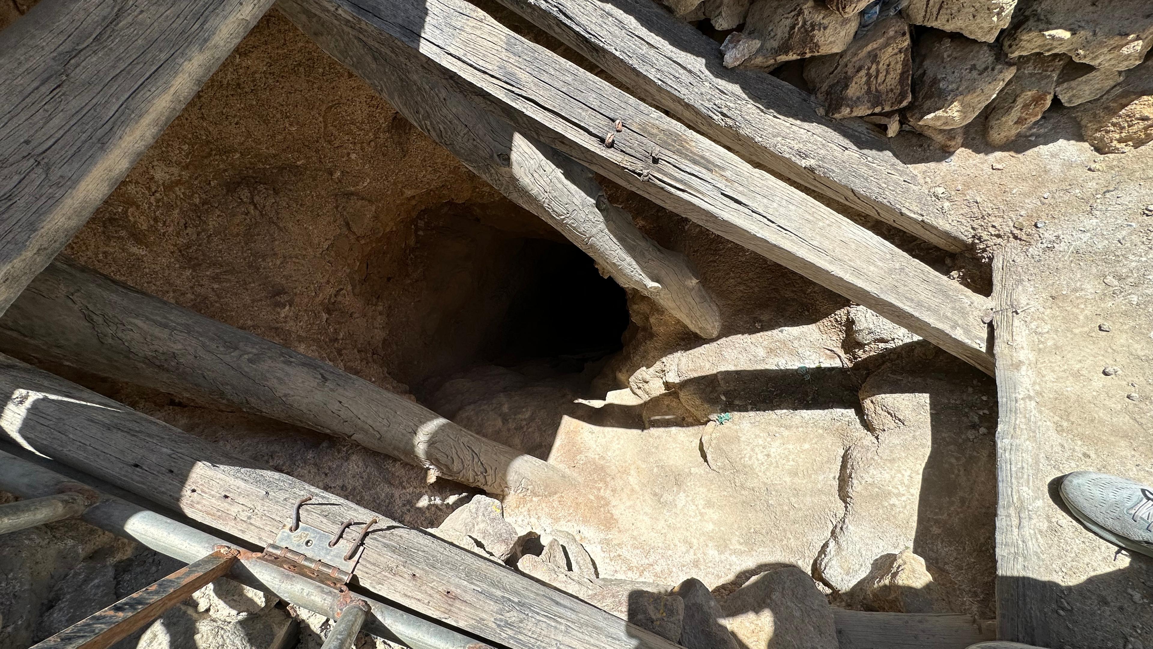 Ein Loch mit Holzbalken zeigt den Eingang in eine Mine
