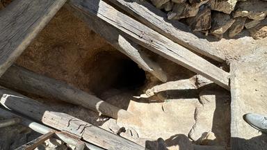 Ein Loch mit Holzbalken zeigt den Eingang in eine Mine
