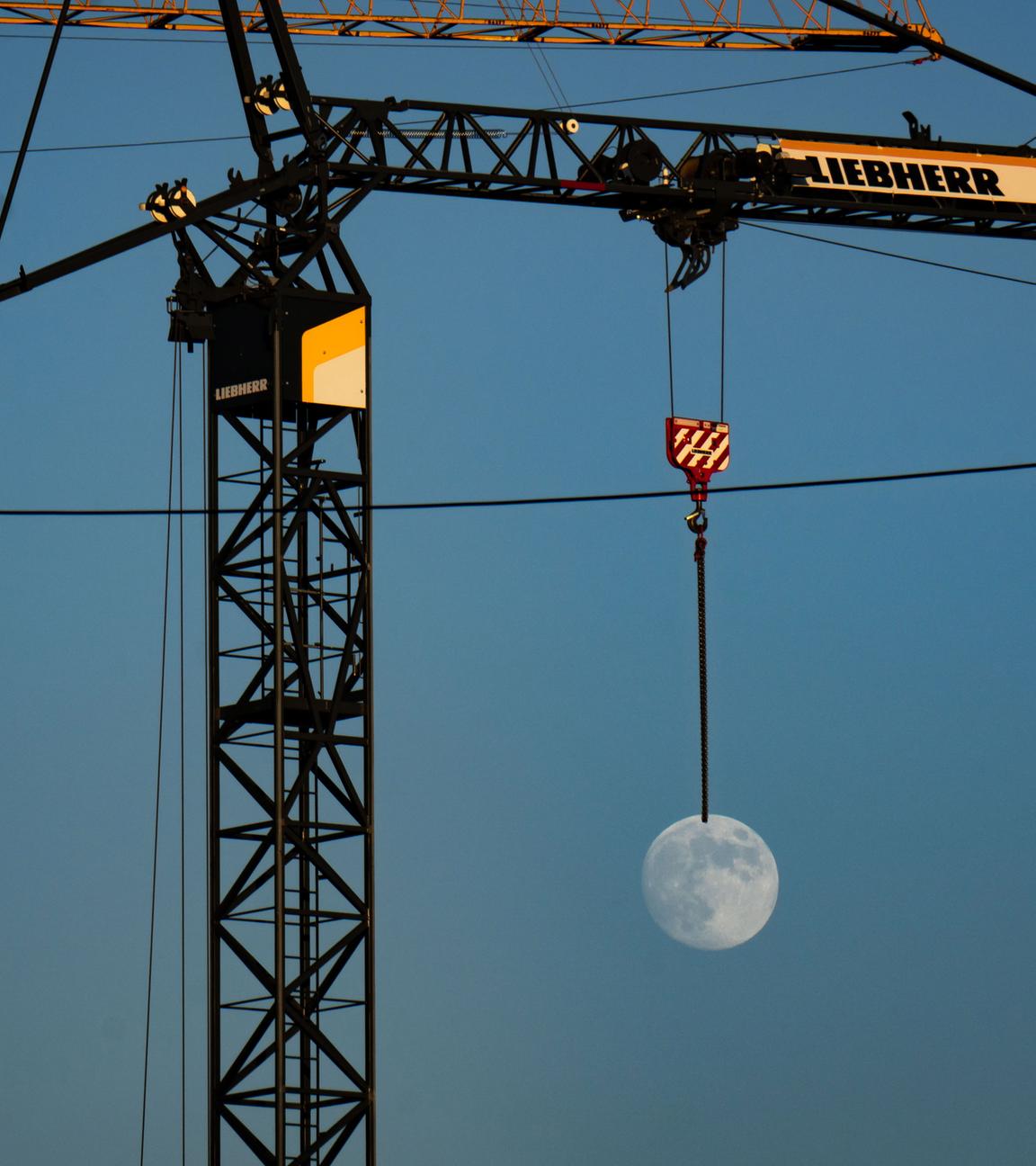 Mond scheint an Baukran zu hängen