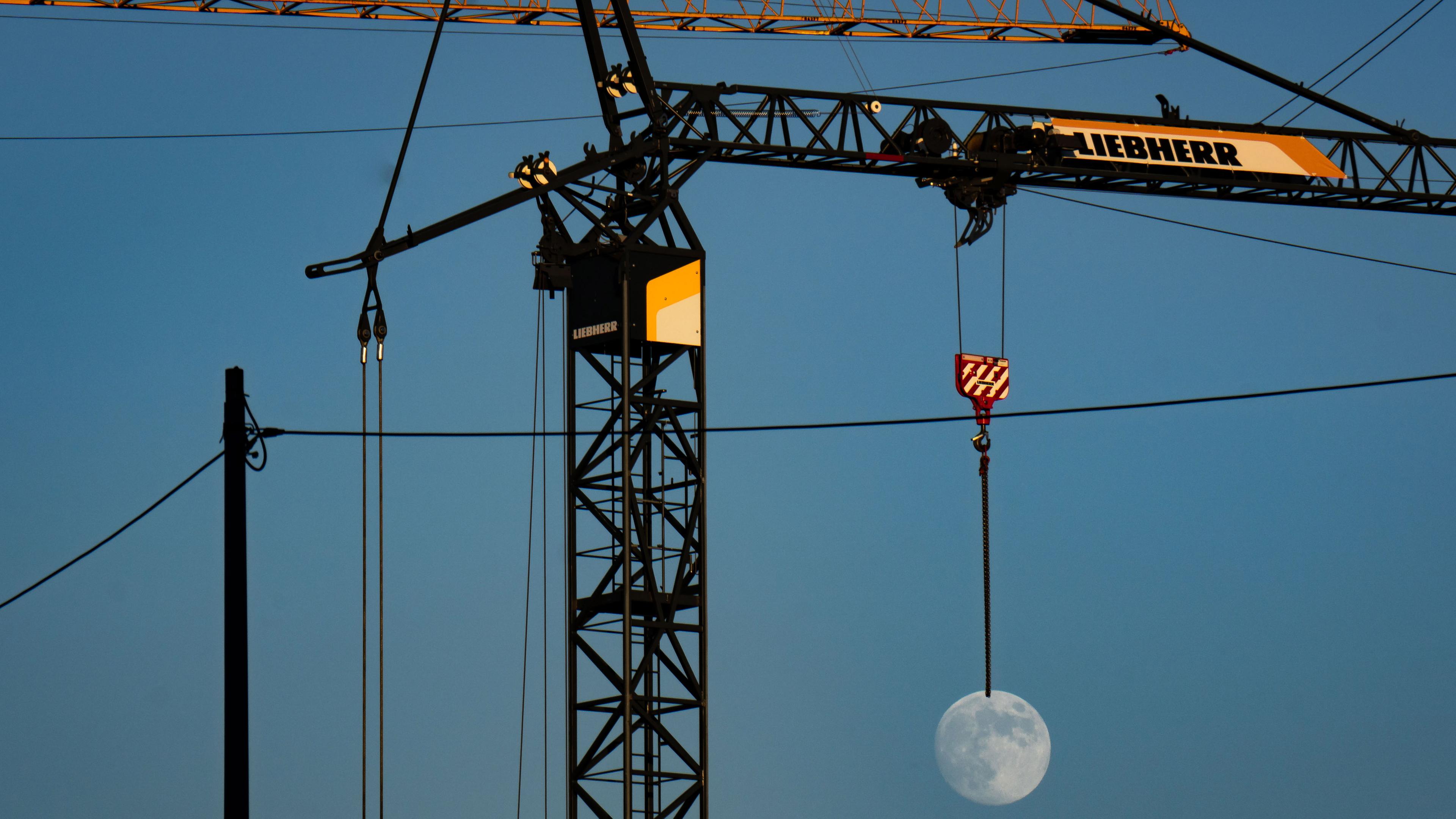 Mond scheint an Baukran zu hängen