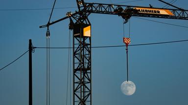 Mond scheint an Baukran zu hängen