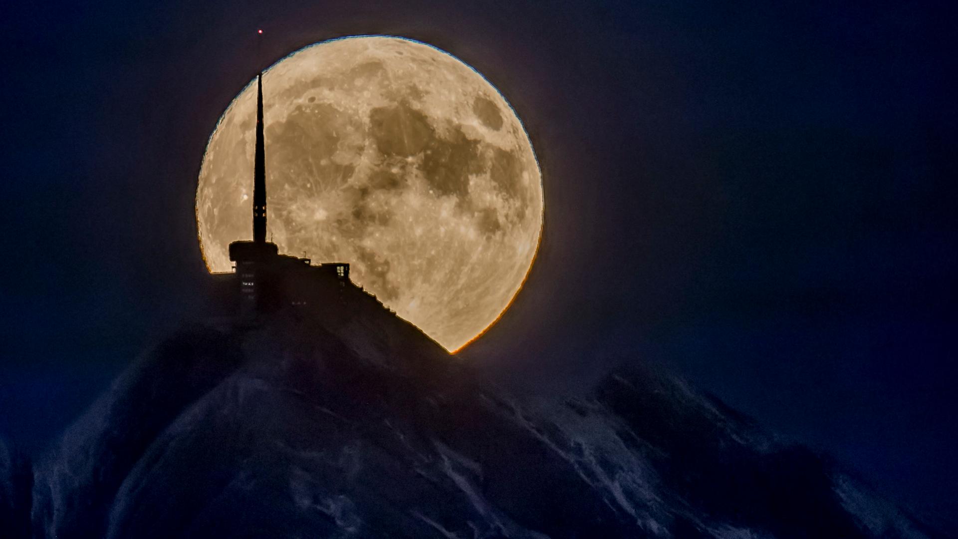 Der Mond zeigt sich in den Schweizer Bergen.