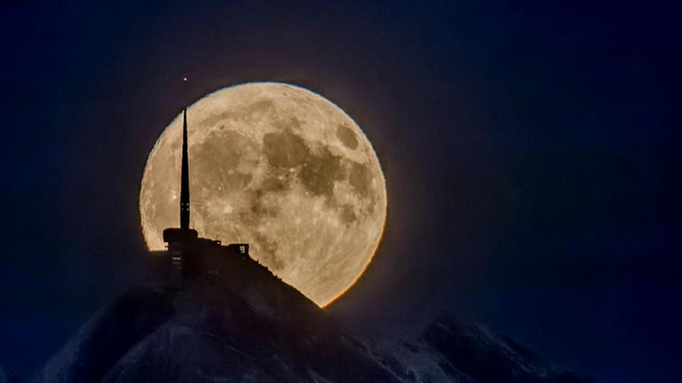 Der Mond zeigt sich in den Schweizer Bergen.