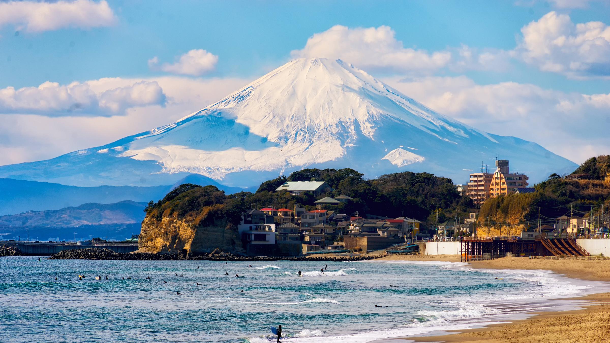 Die Umrisse des Mount Fuji hinter einer Strandpromenade. 