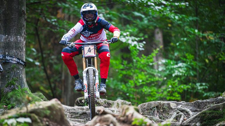 Eine Mountainbike-Fahrerin fährt über Wurzeln und Steine