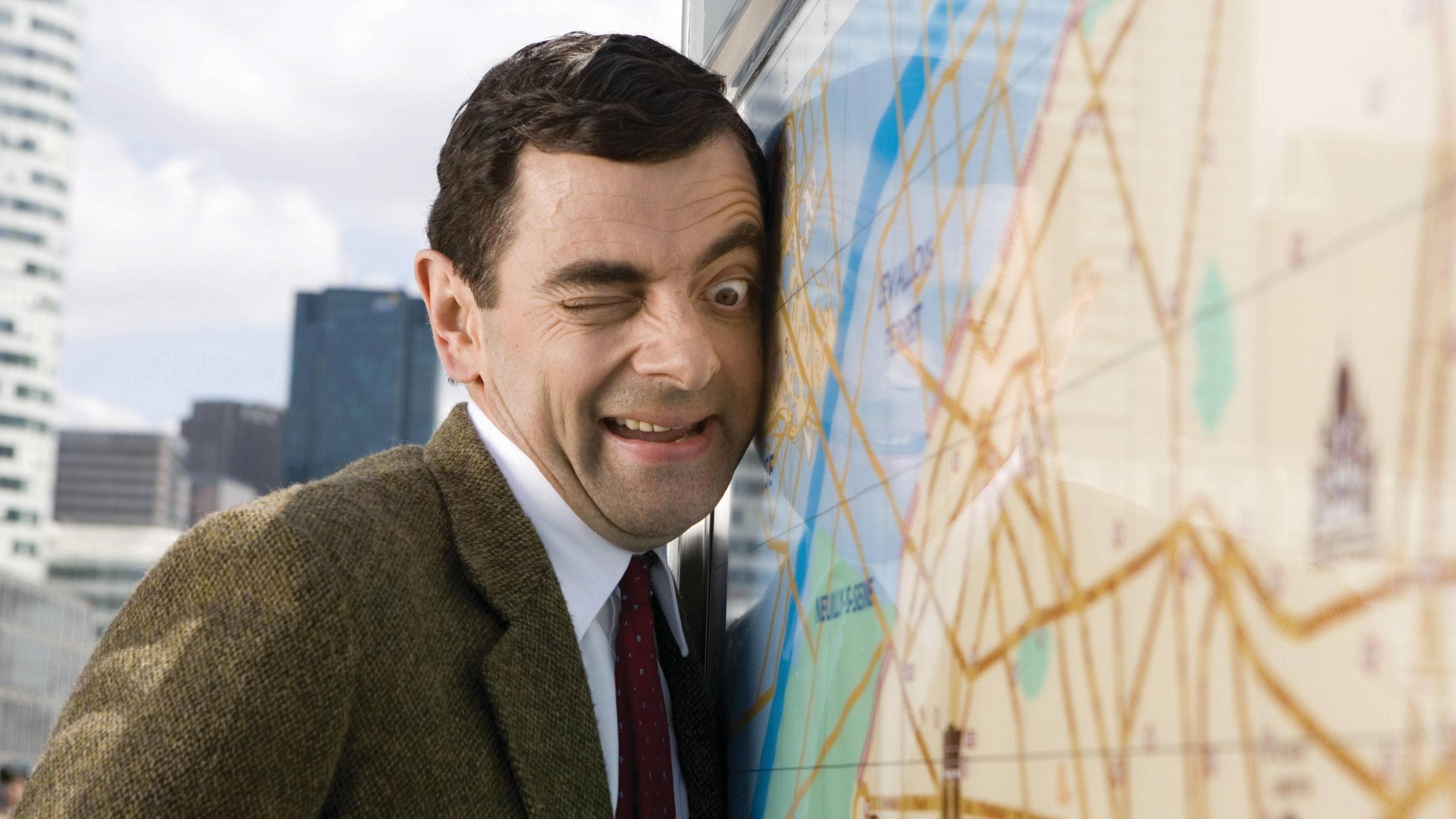Mr. Bean lehnt an einer Weltkugel. 