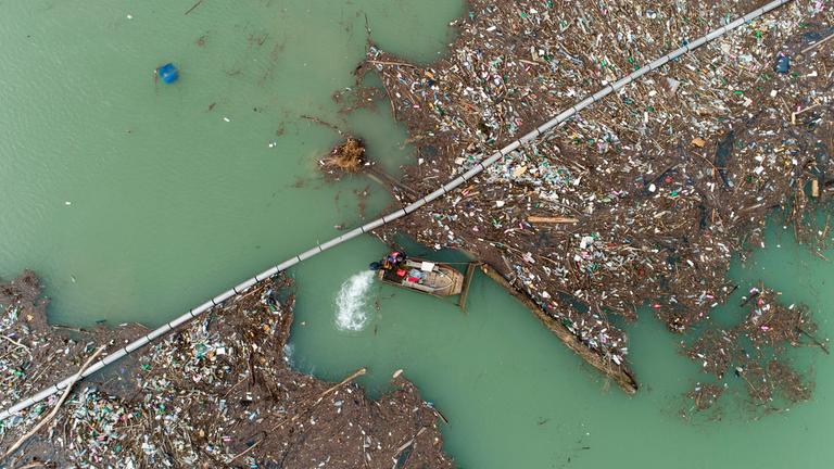 Riesige Müllinseln treiben in einem serbischen Fluss Lim umher. Ein Mann fährt mit einem kleinen Boot durch den Fluss. 