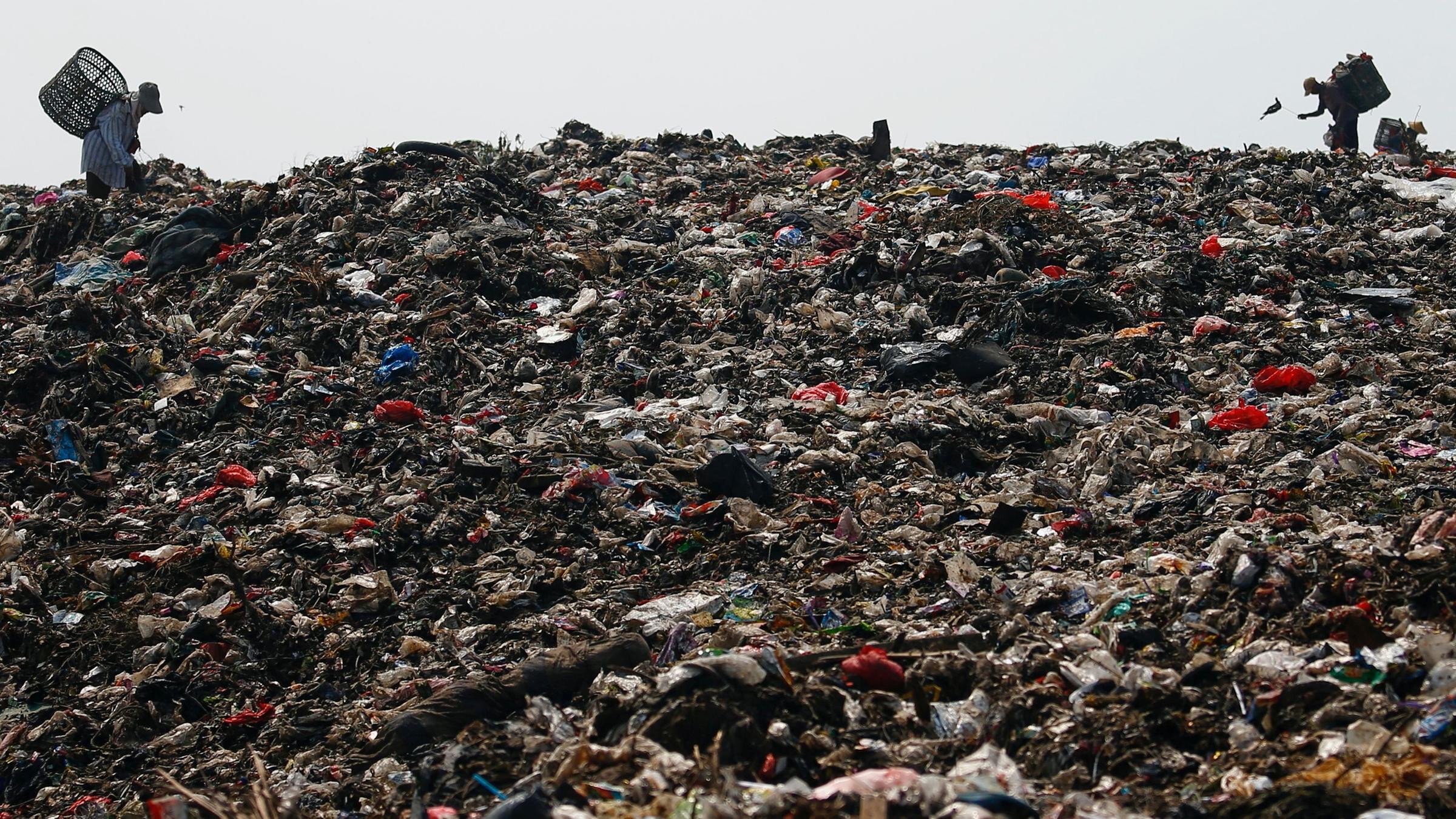 Personen suchen auf einem Muellberg nach recycelbaren Gegenstaenden