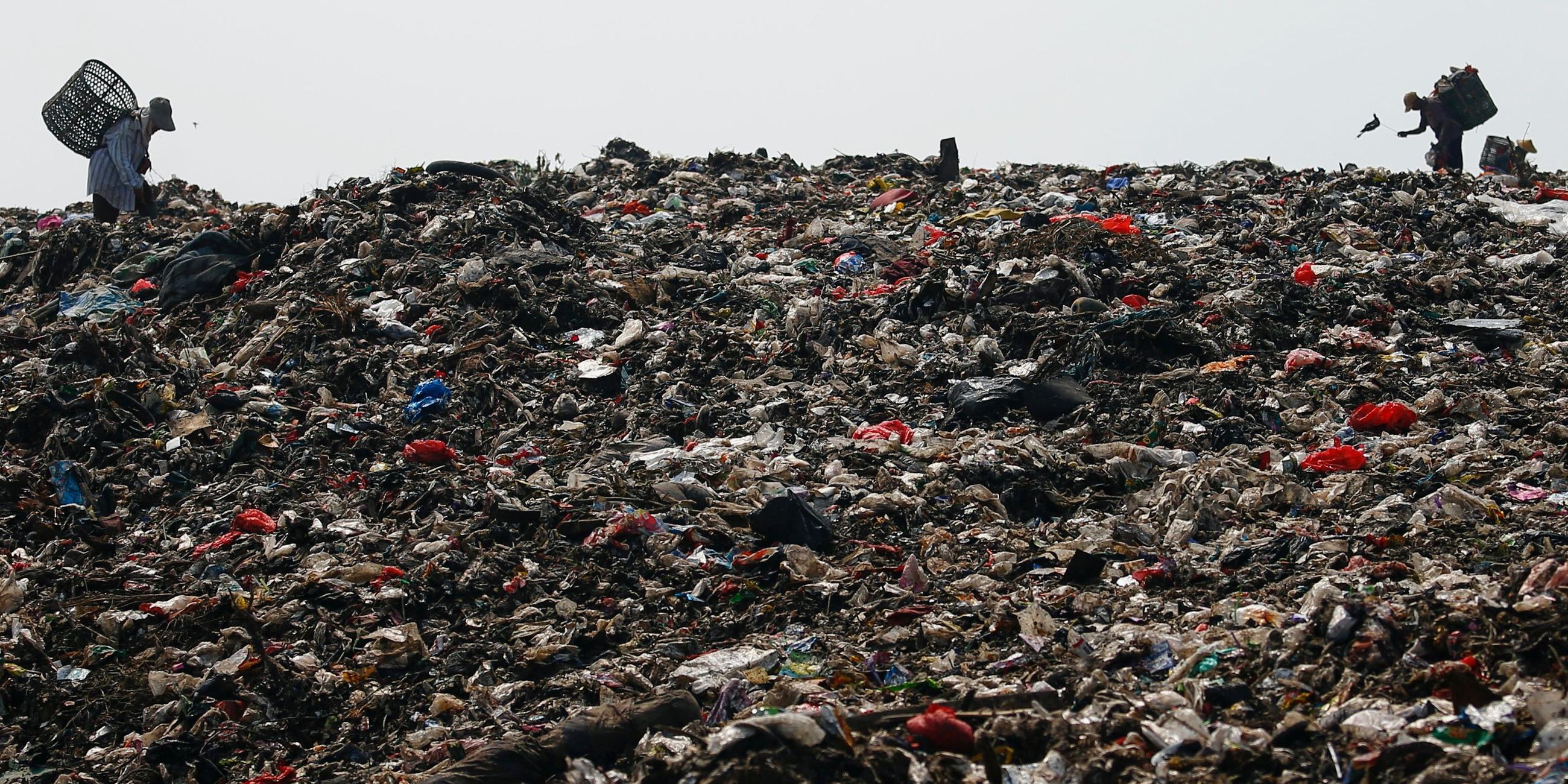 Personen suchen auf einem Muellberg nach recycelbaren Gegenstaenden