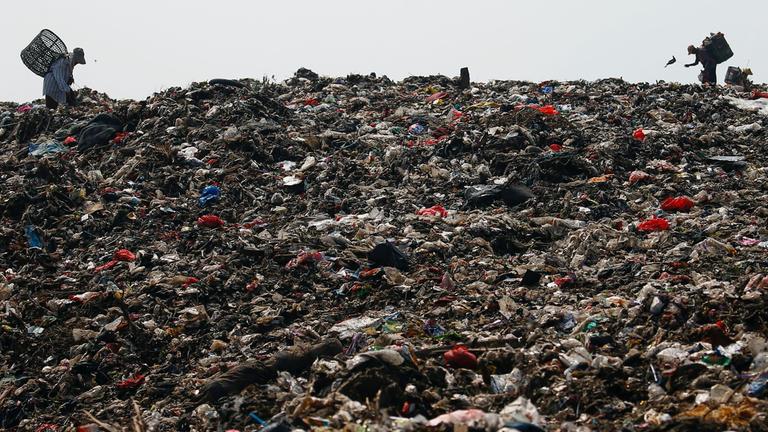 Personen suchen auf einem Muellberg nach recycelbaren Gegenstaenden