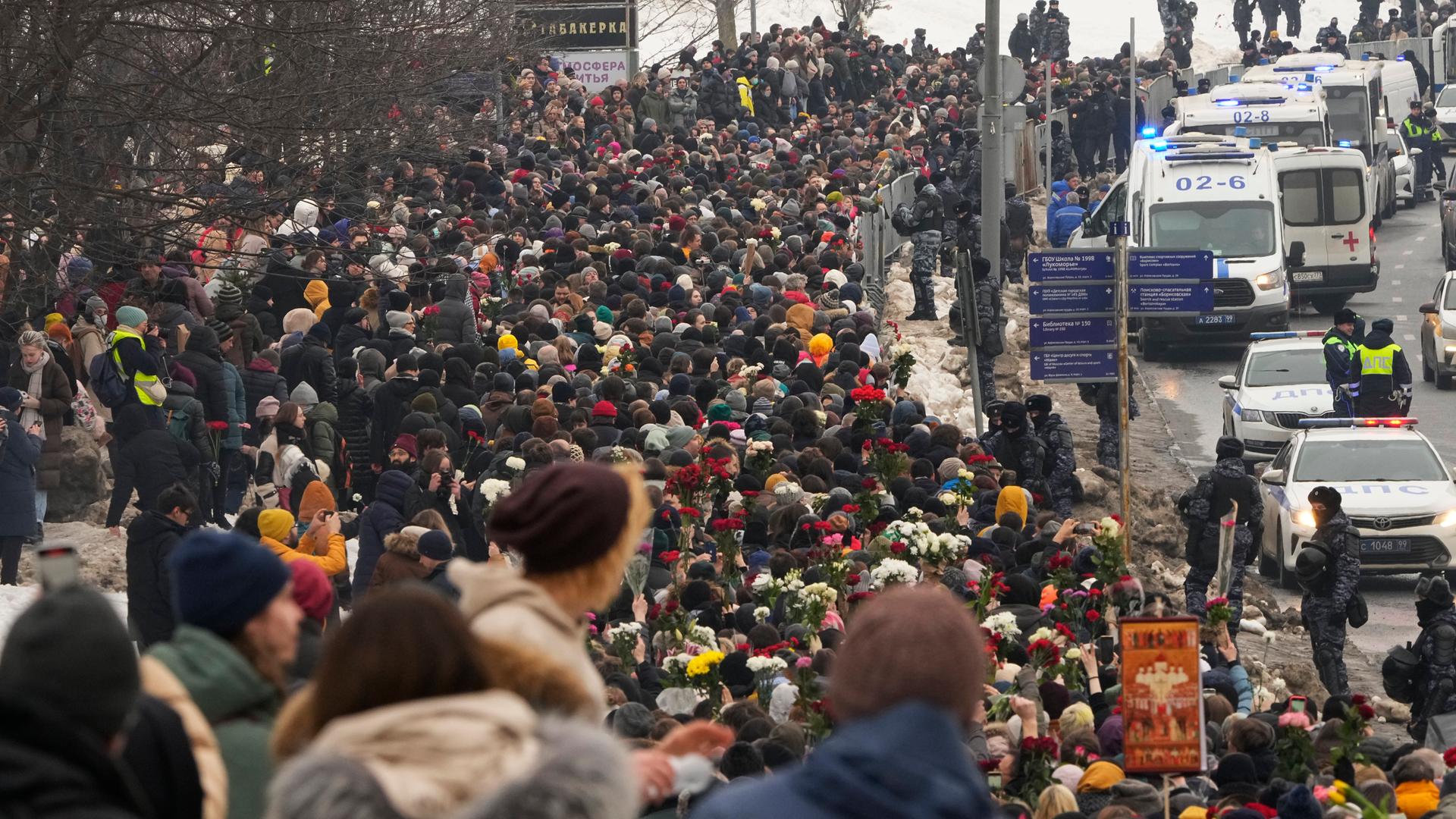 Polizisten (r) beobachten, wie Menschen zur Beerdigungszeremonie des russischen Oppositionellen Nawalny zum Friedhof Borisowskoje gehen