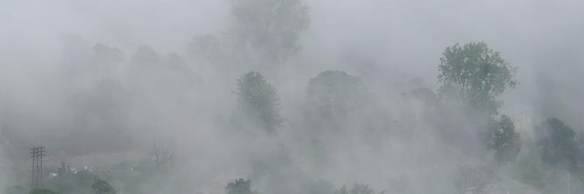 Nebel hüllt eine Ortschaft an einem Berghang in Dharamshala ein.