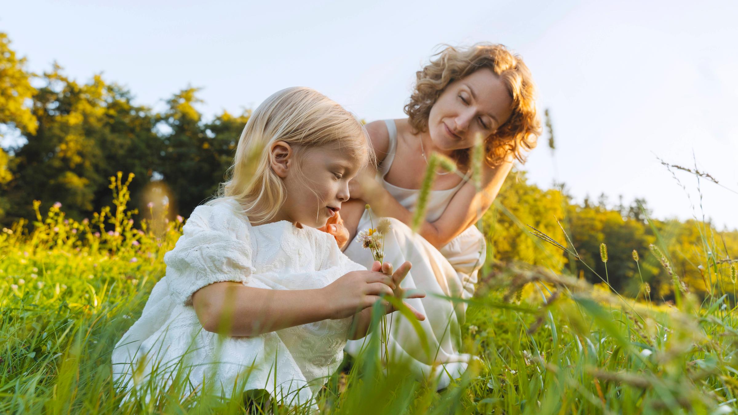 Mädchen und Mutter sitzen auf einer Wiese