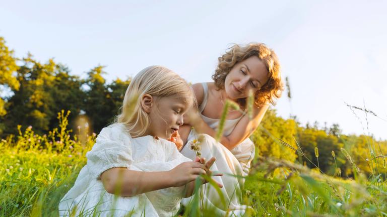 Mädchen und Mutter sitzen auf einer Wiese