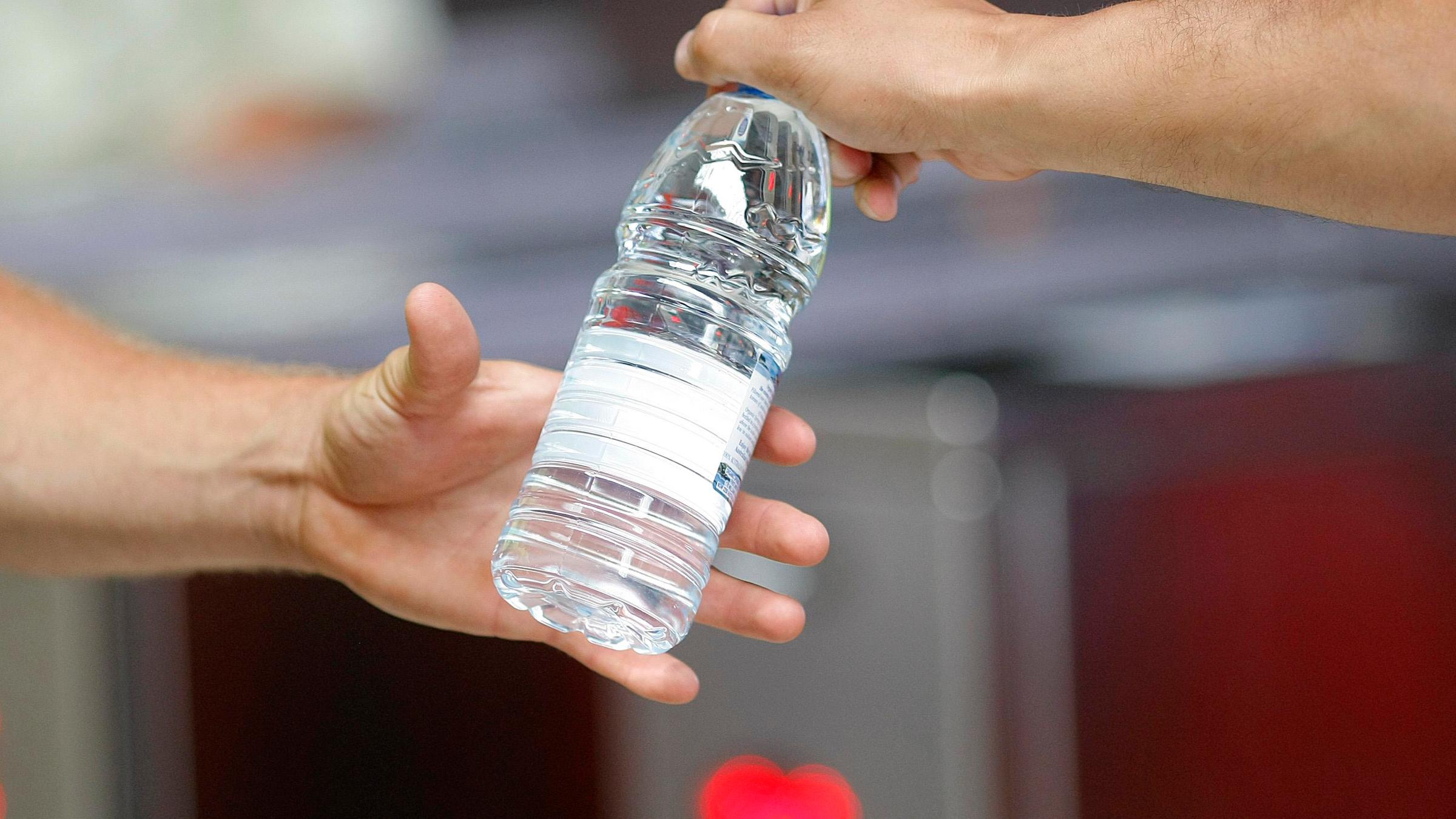 Hand gibt Wasserflasche weiter