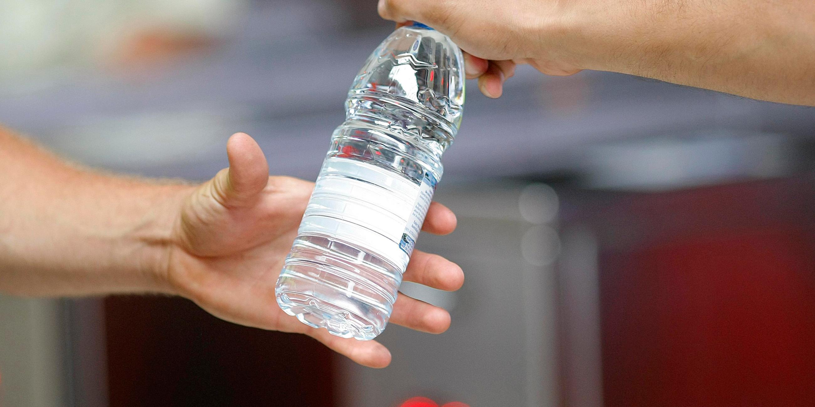 Hand gibt Wasserflasche weiter