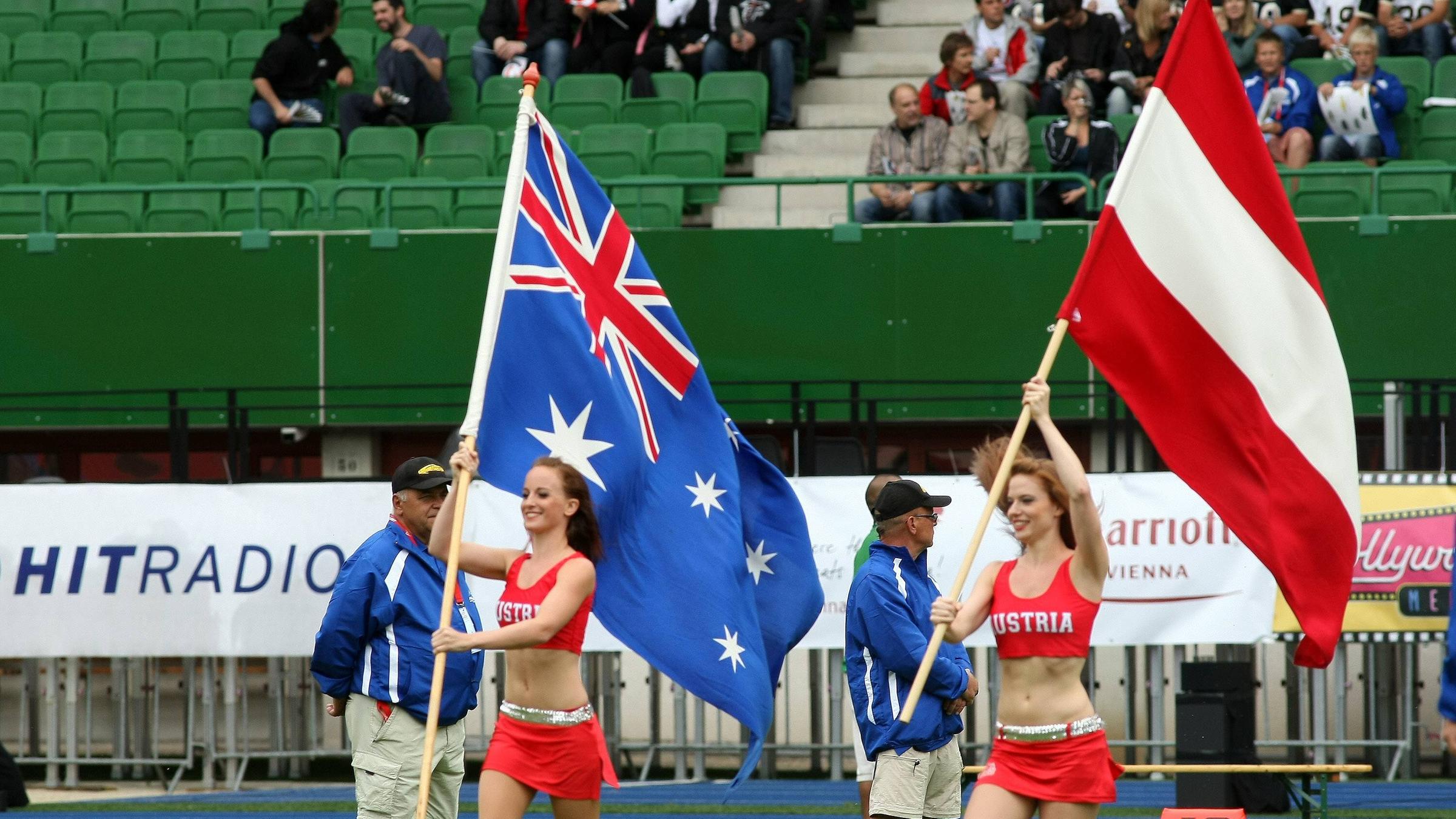 Cheerleader kommen mit den Flaggen von Australien und Österreich auf das Feld