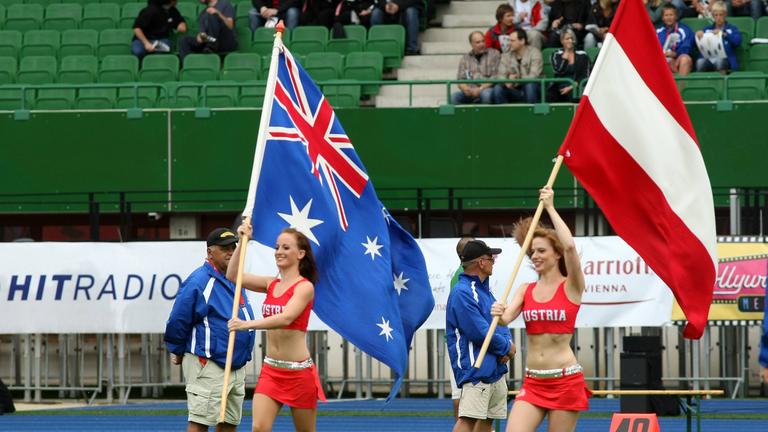 Cheerleader kommen mit den Flaggen von Australien und Österreich auf das Feld