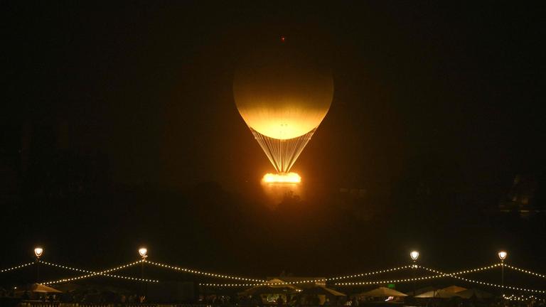 Der Kessel mit der brennenden olympischen Flamme hebt ab, während er an einem Ballon befestigt ist