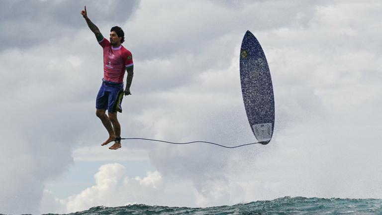 Gabriel Medina post mit seinem Surfbrett in der Luft