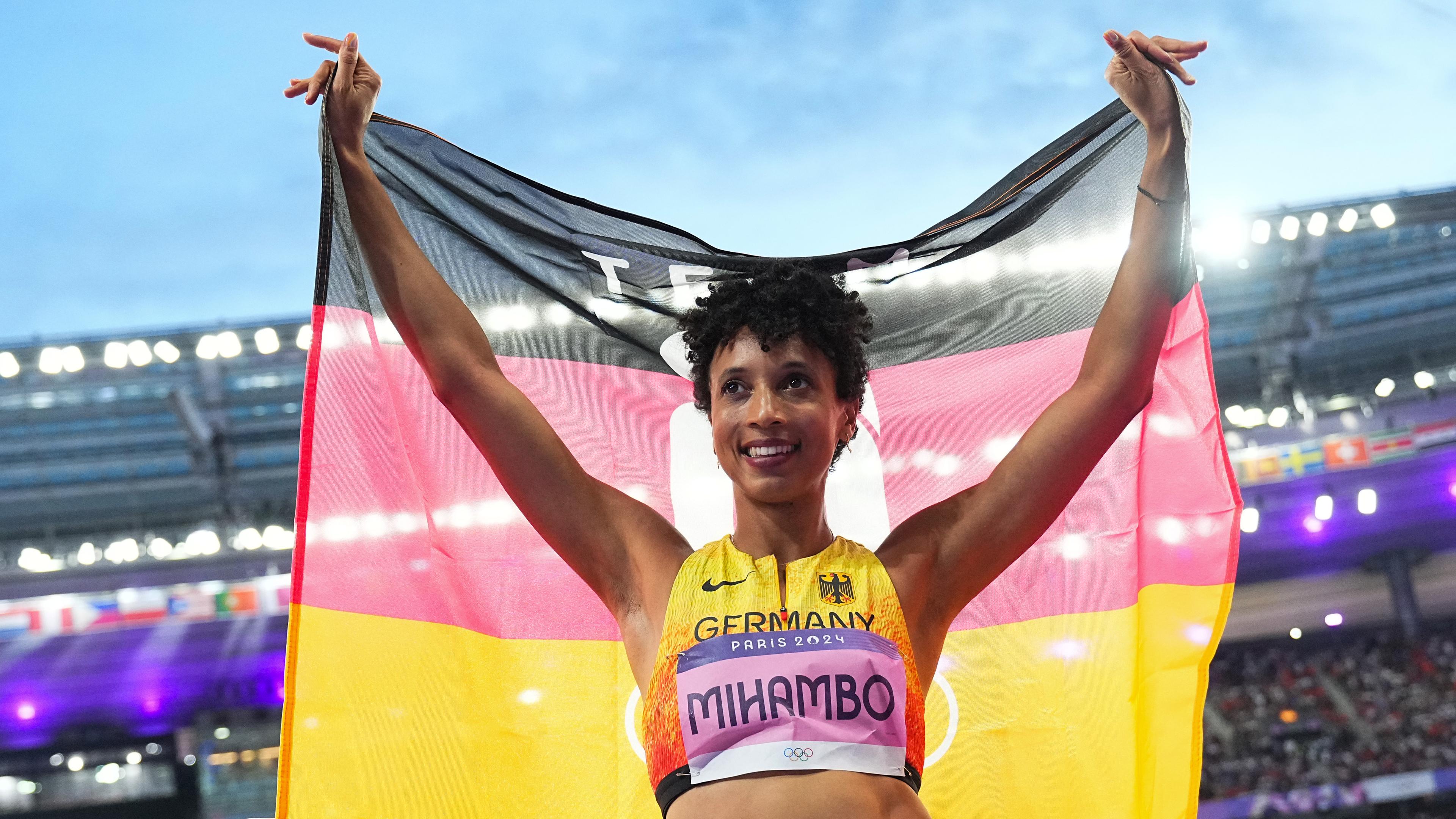 Frau steht im Stadion und hält eine Deutschland Flagge hintersich. 