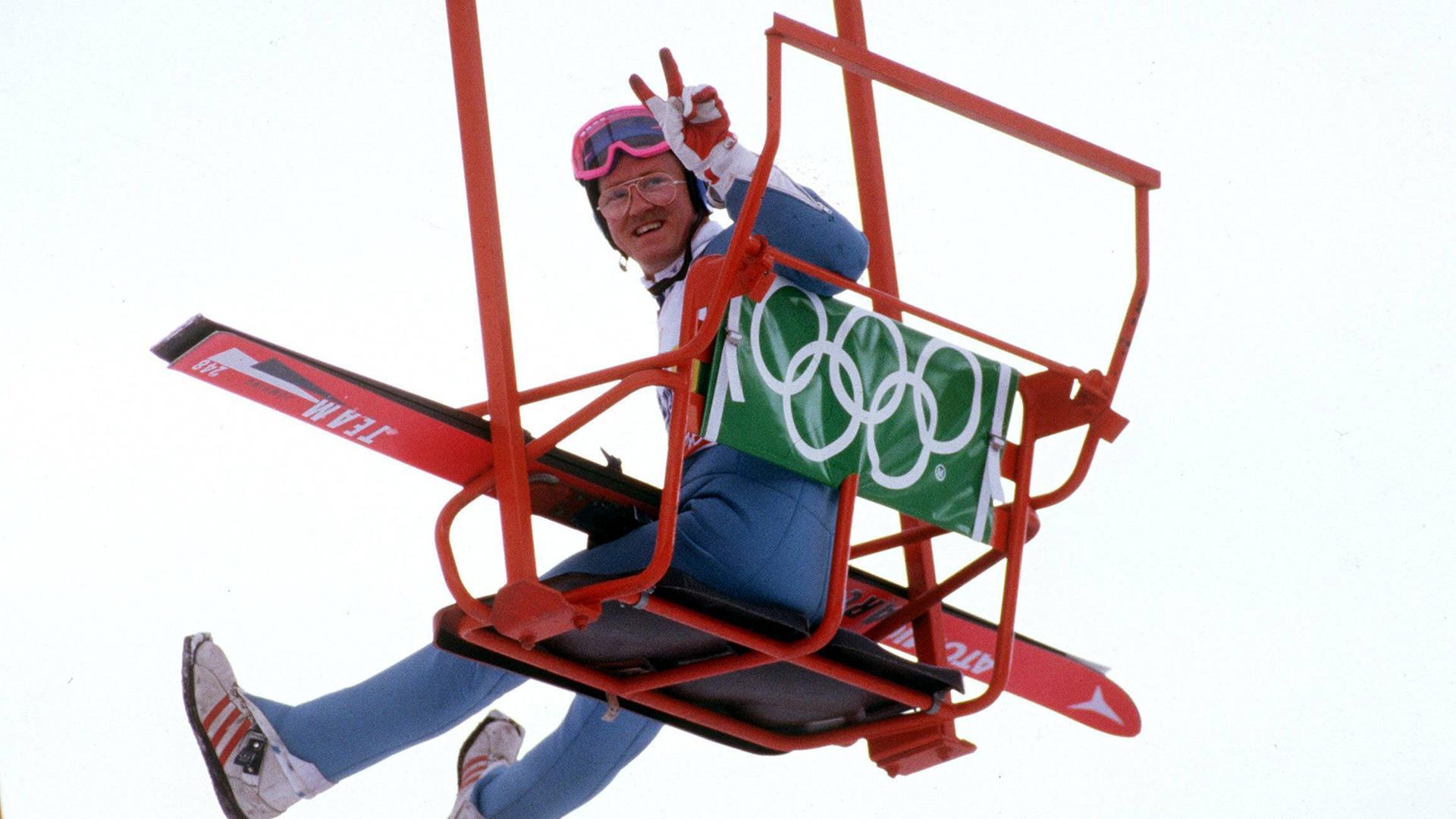 Michael Edwards (Großbritannien) alias Eddie the Eagle grüßt mit dem Peace-Zeichen aus einem Sessellift bei den Olympischen Spielen in Calgary.