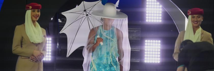 Die Japanerin Naomi Osaka betritt in extravaganten Outfit die Arena für ihr Erstrundenmatch. Sie trägt einen großen weißen Gut, hält einen weißen Schirm und hat einen langen weißen Rock an.