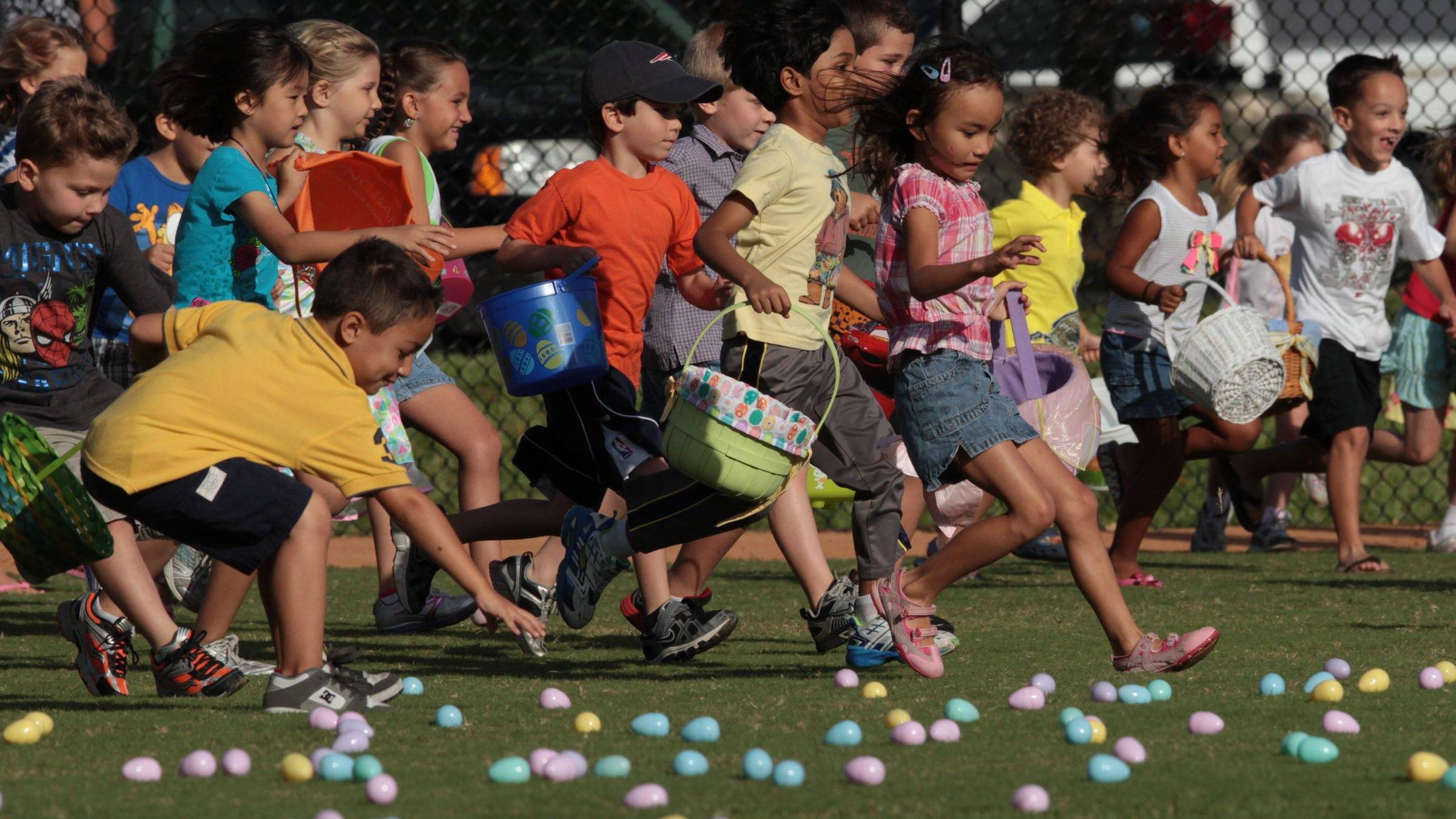 Kinder rennen mit Osterkörbchen über eine Wiese