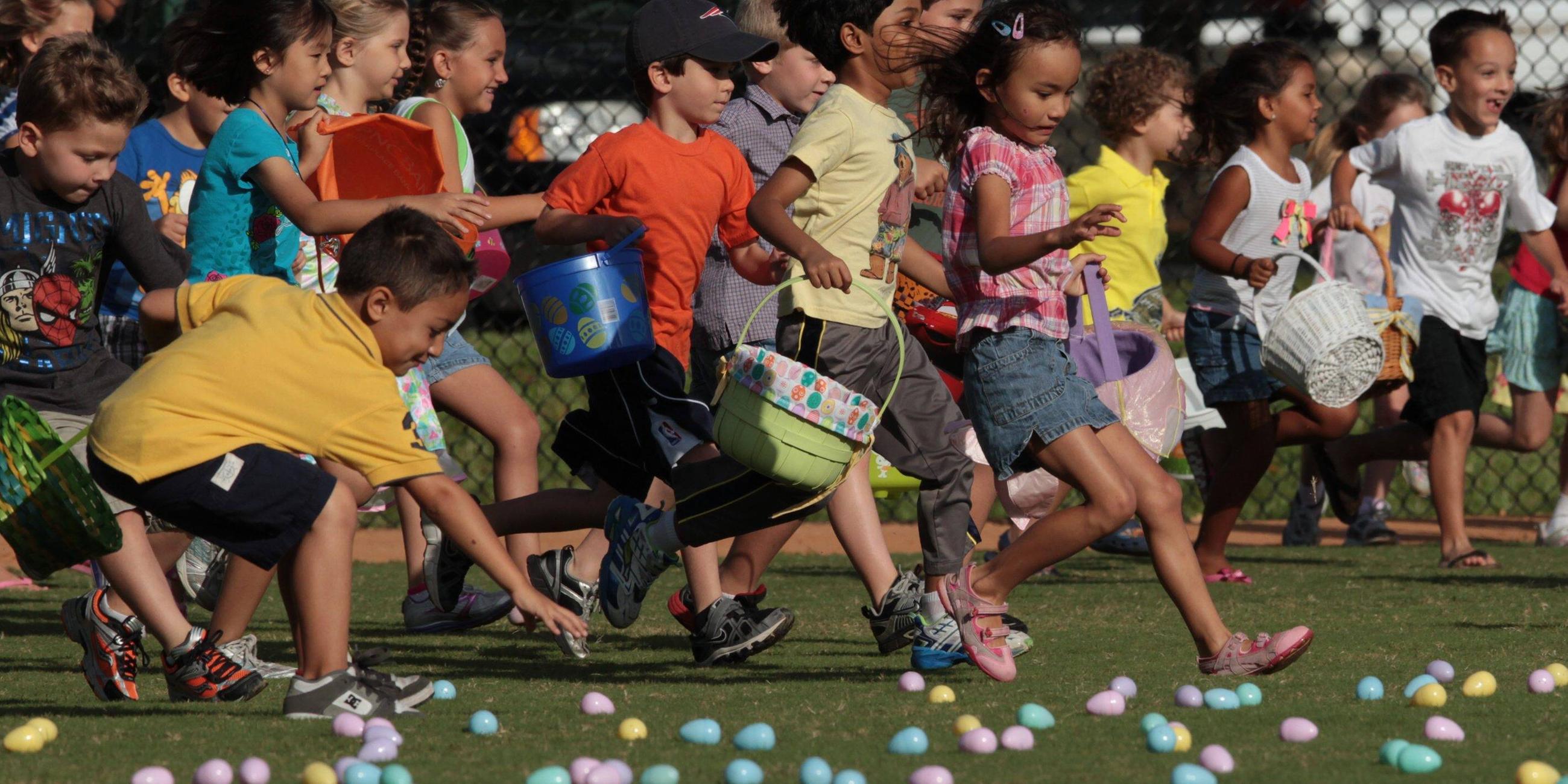 Kinder rennen mit Osterkörbchen über eine Wiese