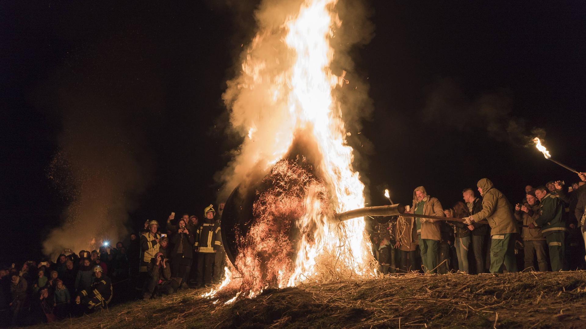 Mit Stroh gefülltes Rad wird angezündet und einen Berg hinunter gerollt.