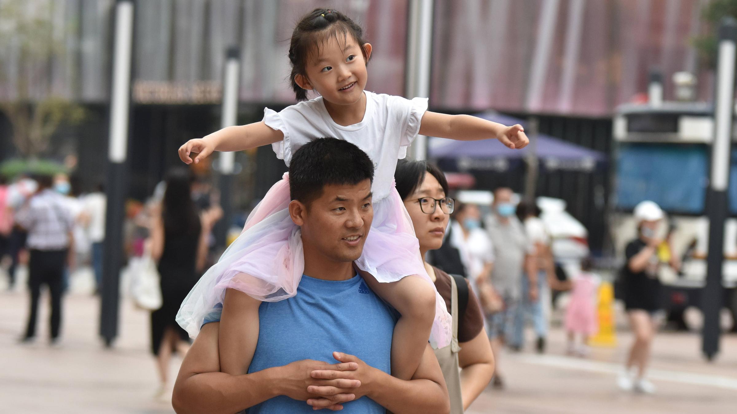 Ein Vater trägt seine Tochter auf der Schulter