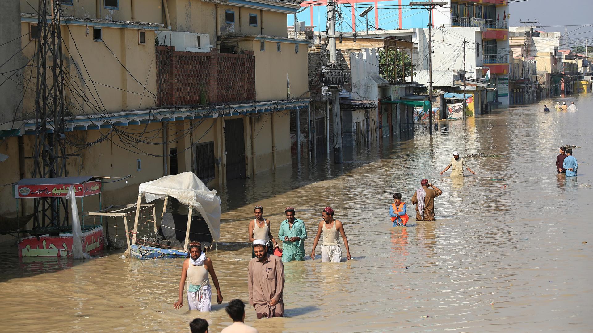 Menschen laufen über eine überflutete Straße in Nowshera