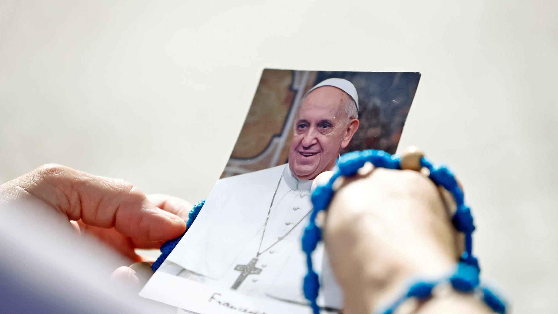 Hände halten Bild von Papst Franziskus