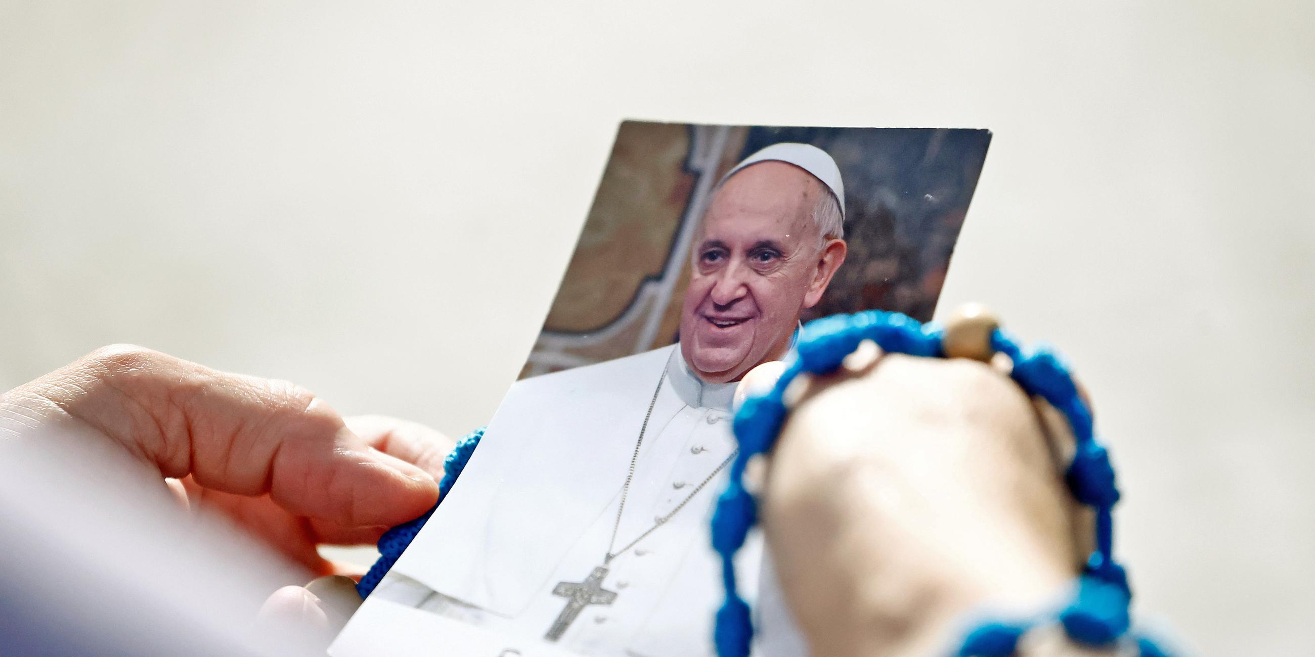 Hände halten Bild von Papst Franziskus