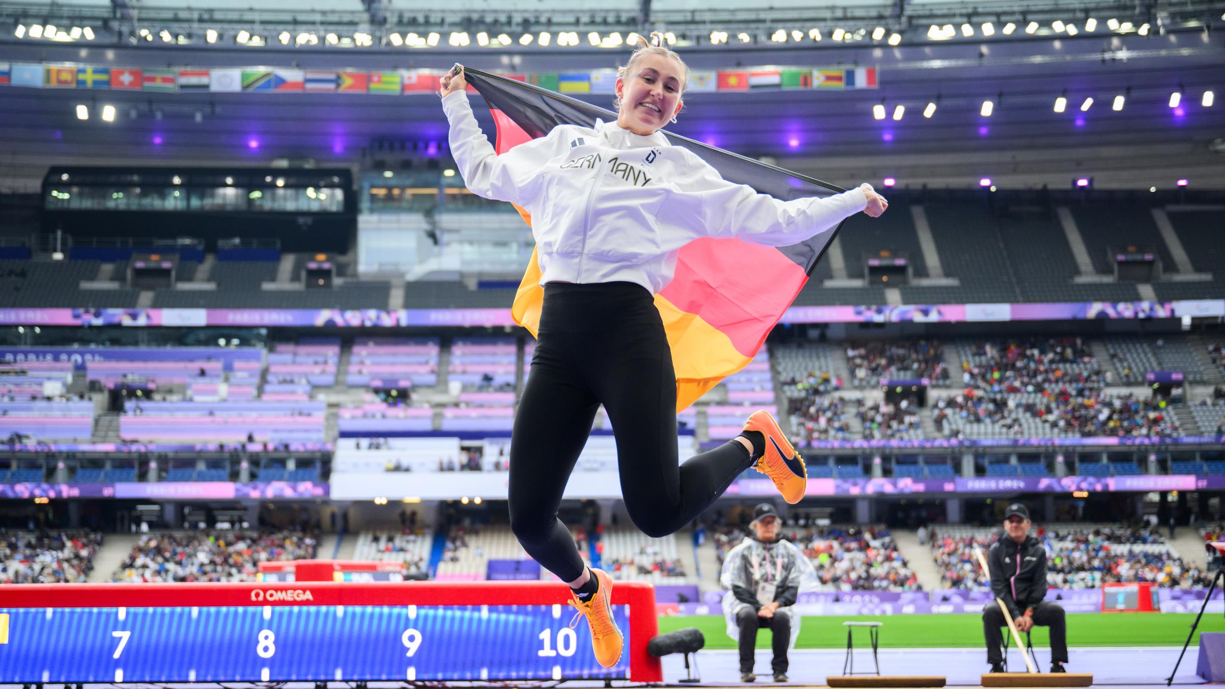 Nele Moos springt in die Luft mit Deutschland Flagge in der Hand