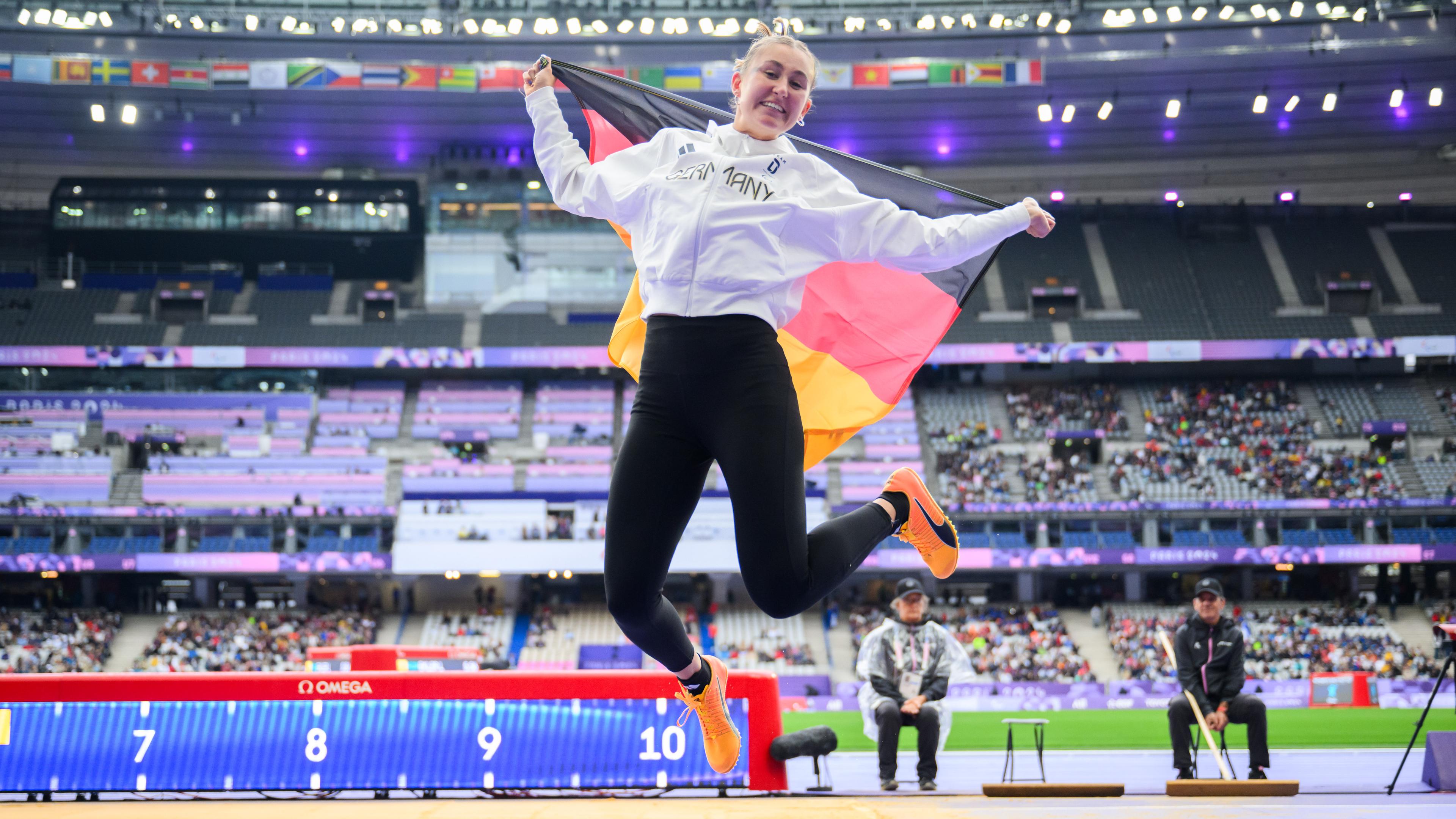 Nele Moos springt in die Luft mit Deutschland Flagge in der Hand